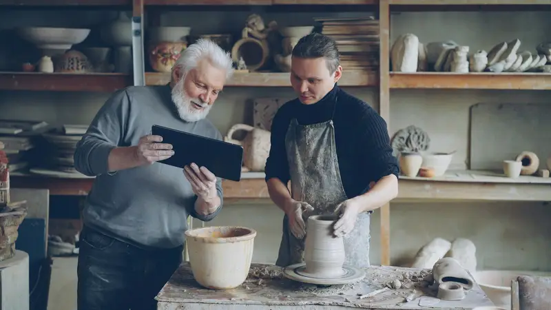 Un dirigeant d'atelier et son artisan consultent un outil métier sur tablette