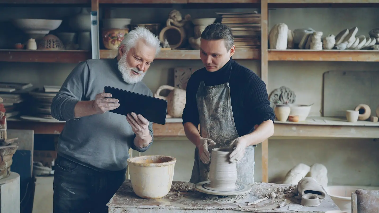 Un dirigeant d'atelier et son artisan consultent un outil métier sur tablette